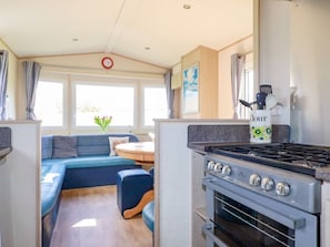 A compact RV kitchen with a stove, oven, and a dining area with a blue sofa.