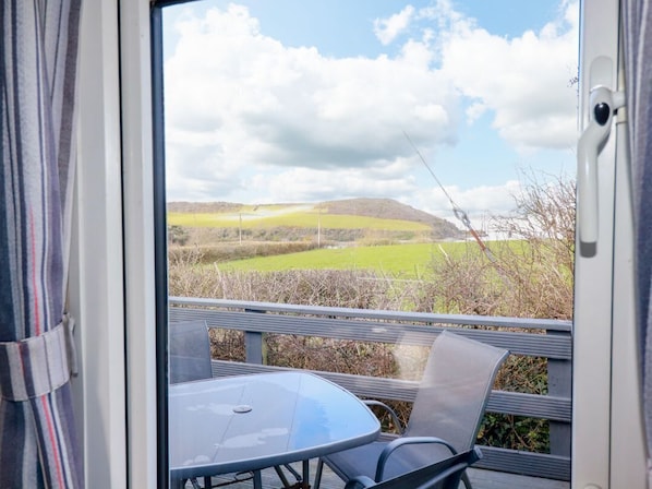 A room with a view of a green landscape, a table, and chairs.