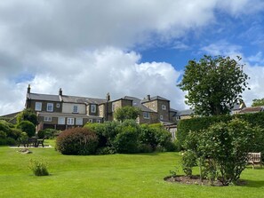A large, multi-story building with a well-maintained lawn and garden in the foreground. - Apartment 1 Sneaton Hall, Sneaton (Whitby)