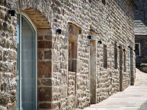 A stone building with arched doorways and a narrow pathway. - The Barn at Amelia's Kitchen Retreat (Skipton)