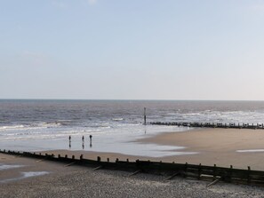 A beach with a wooden jetty, pebbles, and the ocean.