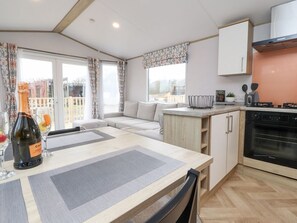 A modern kitchen with a dining area, a built-in oven, and a view of the outdoors. - Giorgio, Warton in Lancashire. (Preston)
