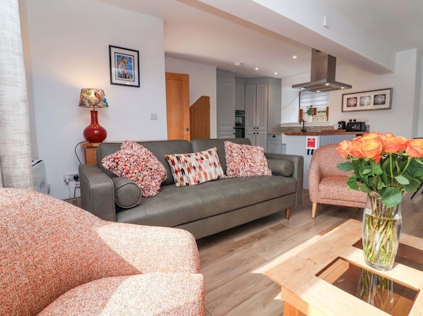 A living room with a sofa, a coffee table, and a vase with flowers.