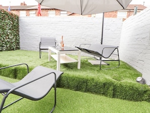 A patio area with a white brick wall, a hedge, and a table with chairs. - 28 Empress Road, Liverpool (Liverpool)