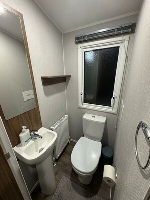 Une petite salle de bain avec des toilettes, un lavabo et une fenêtre.