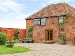 A brick building with a tiled roof, a wooden door, and a gravel driveway. - Charming Barn Owl Retreat in Louth (Louth)