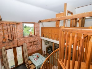A loft-style room with a brick wall, wooden ceiling, and a dining table with chairs. - Charming Barn Owl Retreat in Louth (Louth)