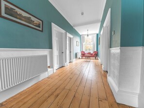 A hallway with wooden flooring, white wainscoting, and a red sofa in the distance. - 8 Corkickle, Whitehaven (Whitehaven)