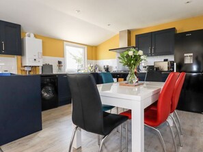 A modern kitchen with a dining area, a built-in washing machine, and a central island.