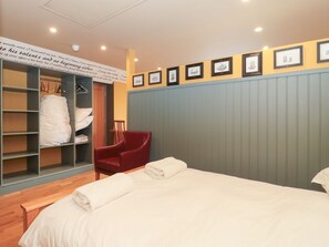 Ein Hotelzimmer mit einem Bett, einem roten Sessel, einem Kleiderschrank und gerahmten Bildern an der Wand.