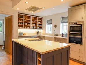 A modern kitchen with built-in shelves, a central island, and double ovens. - Fern Cottage, Elsworth, Cambridge (Cambridge)