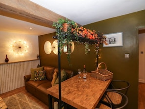 Ein gemütliches Wohnzimmer mit Holztisch, einer Couch, einer Zierpflanze und einem gerahmten Bild an der Wand.