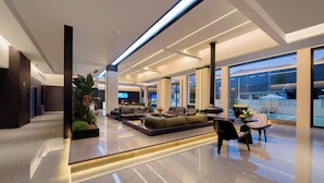 A modern hotel lobby with a seating area, large windows, and a view of the outdoors. - Forest Oxygen Bar Resort Hotel (Zhangjiajie)