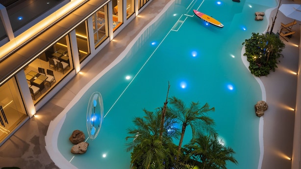 A swimming pool with a lounge area, a glass balustrade, and a view of the building's interior. - Forest Oxygen Bar Resort Hotel (Zhangjiajie)