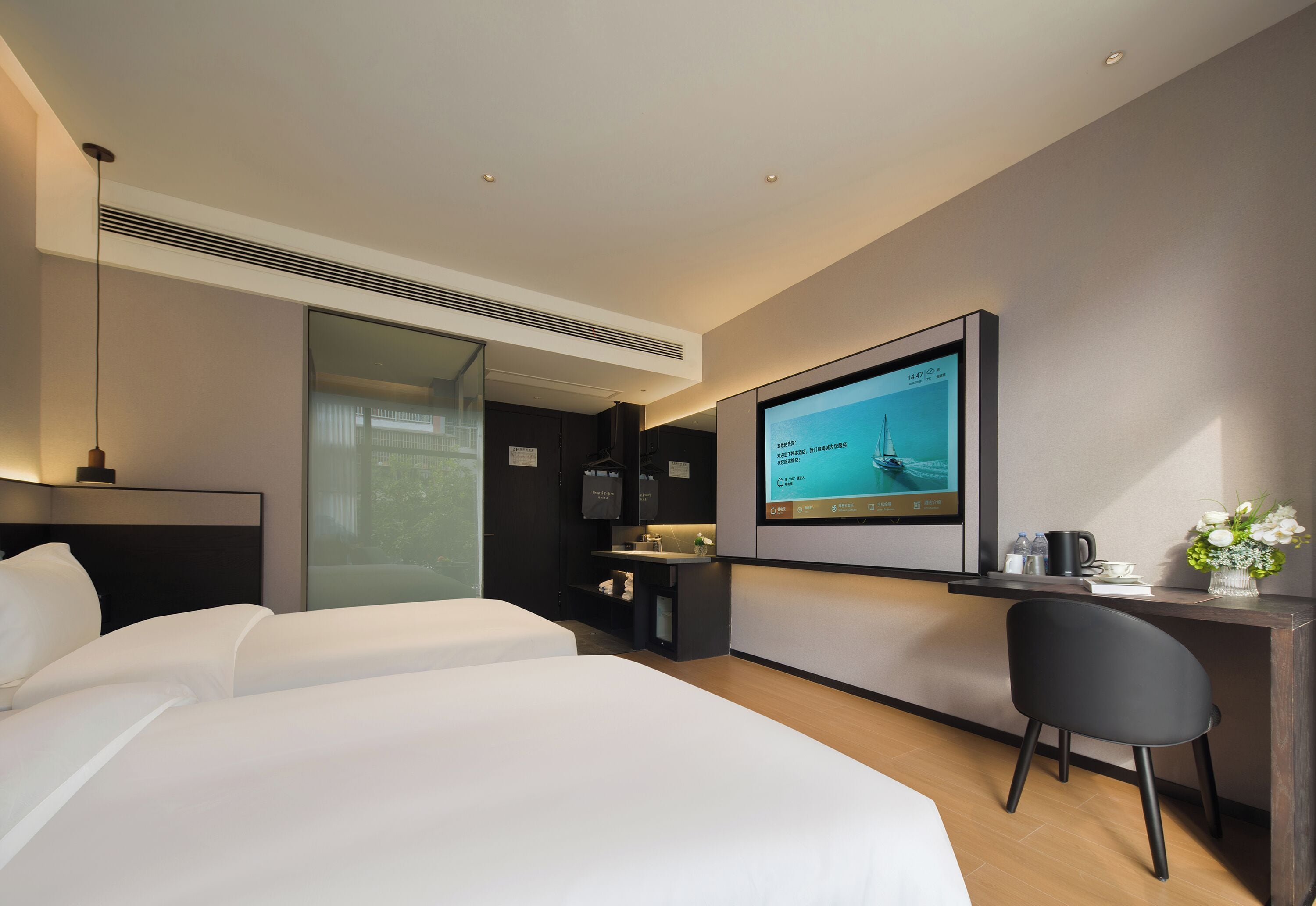 Ein modernes Hotelzimmer mit einem großen Bett, einem Schreibtisch mit Computer und einem Fernseher, der eine Speisekarte zeigt.