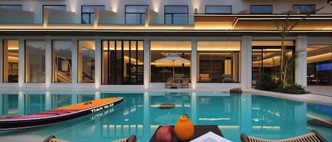 Una piscina al aire libre, sillones reclinables de piscina