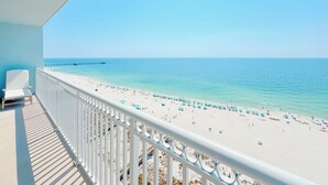 A balcony with a view of a beach, a pier in the distance, and a clear sky. - Colonnades 1403 | Completely updated! Gorgeous condo, beachfront, sleeps 12! (Gulf Shores)