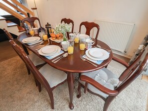 A dining table set with plates, cutlery, glasses, and a vase of flowers. - Cromer Holiday Home, Cromer (Cromer)