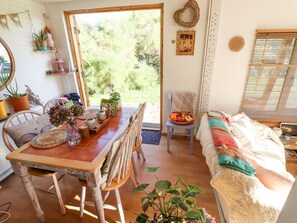 A cozy room with a wooden dining table, a sofa, and a window with blinds.