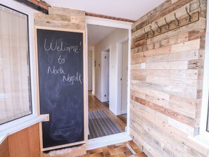 A hallway with a blackboard displaying 'Welcome to North Abroad,' wooden paneling on the walls, and a door leading to another room. - Charming Woodview Home Near Grove Fm (Norwich)
