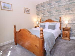 A bedroom with a wooden bed, two bedside tables with lamps, a grey carpet, and a wall with a wooden plank pattern. - Charming Woodview Home Near Grove Fm (Norwich)