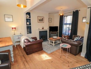 A living room with a fireplace, leather sofas, a TV, and a dining area. - 1 Albion Place, Whitby (Whitby)
