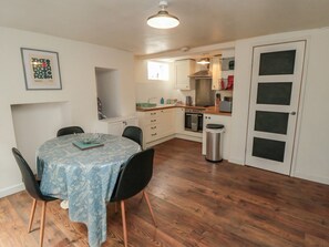 A compact kitchen with a dining area, a trash bin, and a framed picture on the wall. - 1 Albion Place, Whitby (Whitby)