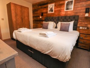 Quarto com uma cama grande, paredes de painel de madeira, um guarda-roupa e uma mesa de cabeceira.