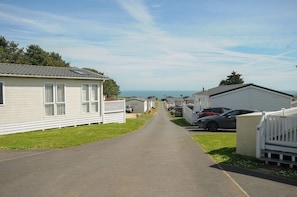 Un parc de caravanes doté d’une allée pavée, de caravanes blanches et offrant une vue dégagée sur la mer.