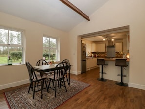 A dining area with a table and chairs, a kitchen in the background, and a view of the outdoors. - Heathfield in Milverton, rural (Taunton)