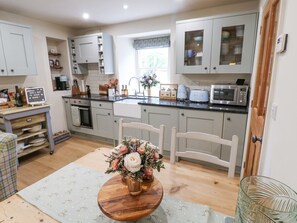 Una cocina con armarios grises claros, una mesa de comedor de madera con un centro de mesa floral y un microondas en la encimera.