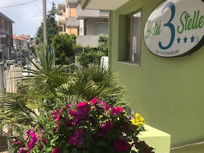 Un edificio con un letrero que dice 'Hotel 3 Stelle' y una jardinera con flores.