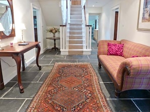 A living room with a sofa, a table, a rug, and a staircase. - Easter Urray Farmhouse, Muir Of Ord (Muir of Ord)