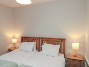A bedroom with a wooden headboard, two bedside tables with lamps, and a bed with white bedding.