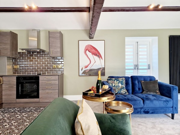 A modern kitchen with a brick backsplash, a dining area with a blue sofa, and a framed artwork of a flamingo.