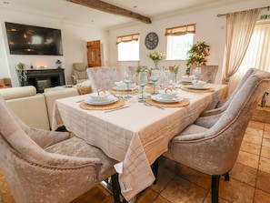 A dining room with a long table set for six, surrounded by plush chairs, a fireplace, and a large wall clock. - The Wing, Bangor-On-Dee, Wales (Wrexham)