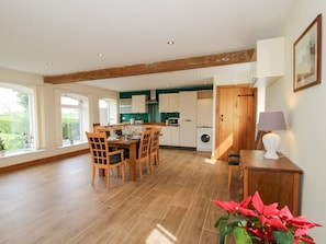 A spacious kitchen with wooden beams, a dining area with a table and chairs, and a view of the outdoors.