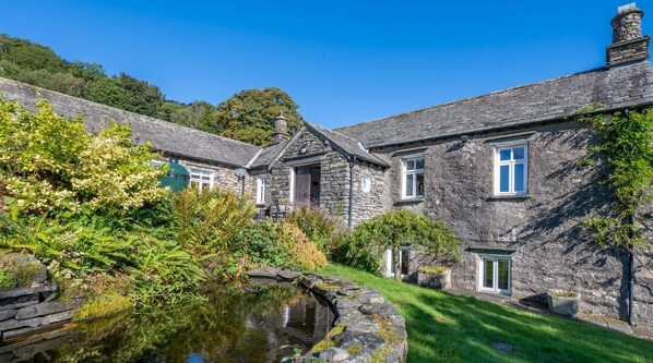 A stone building with a pond, surrounded by greenery. - Field Head House, Hawkshead (Ulverston)