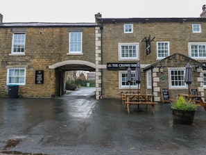 A stone building with a sign for 'The Crown Inn' and a covered outdoor seating area.