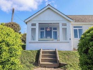 A single-story house with a front porch, a set of stairs leading to the entrance, and a clear sky.