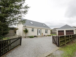 Una casa d'habitatge amb un camí de grava, una tanca de fusta i un garatge.