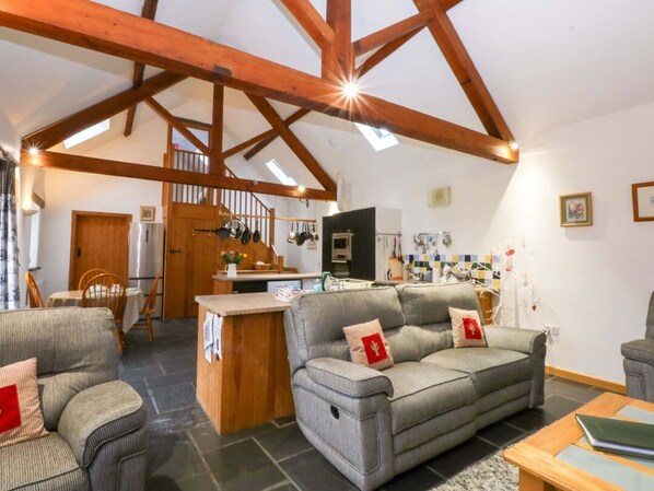 A spacious living area with a sofa, a dining table, and a kitchen in the background.
