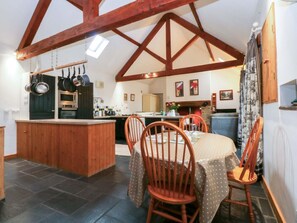 A kitchen with wooden beams, a dining table with chairs, and a small island.