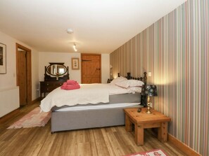 A bedroom with a bed, bedside table, lamp, and a striped wall.