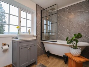 A bathroom with a bathtub, a window, a sink, and a cabinet. - 4 Lilac Cottages, Ainthorpe (Whitby)