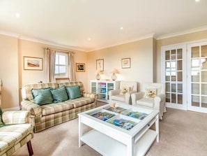 A living room with a plaid sofa, a white coffee table with magazines, and a white armchair. - Little Laight, Stranraer (Stranraer)