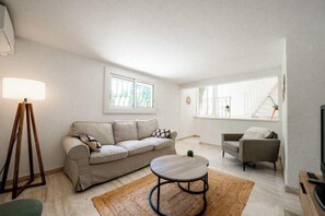 Ein Wohnzimmer mit einer Couch, einem Couchtisch, einer Lampe und einem Fernseher.
