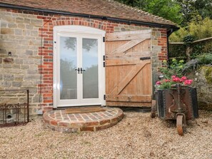 A stone building with a white door and a wooden gate. - Hungers Cottage, Petworth. (Petworth)