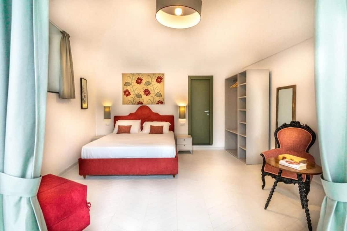 A bedroom with a bed, bedside tables, a chair, a wardrobe, and a painting on the wall.