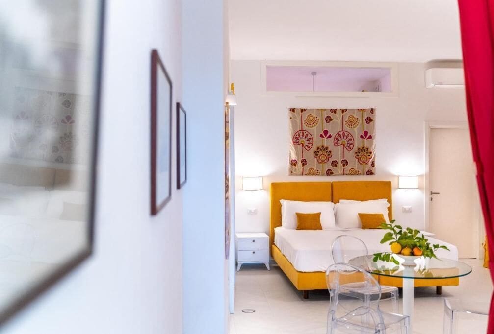 Een slaapkamer met een bed, nachtkastjes, een glazen salontafel en een gordijn met een patroon.